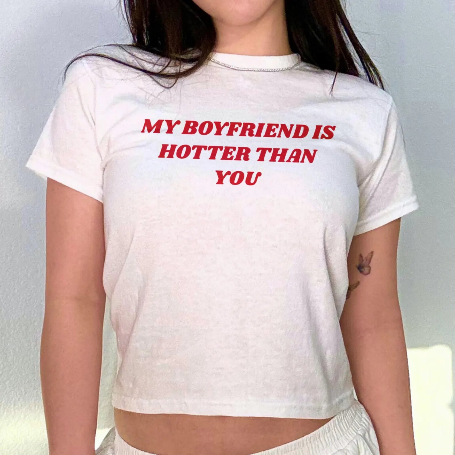 Model wearing a white T-shirt reading 'MY BOYFRIEND IS HOTTER THAN YOU', showcasing a fun and playful style.